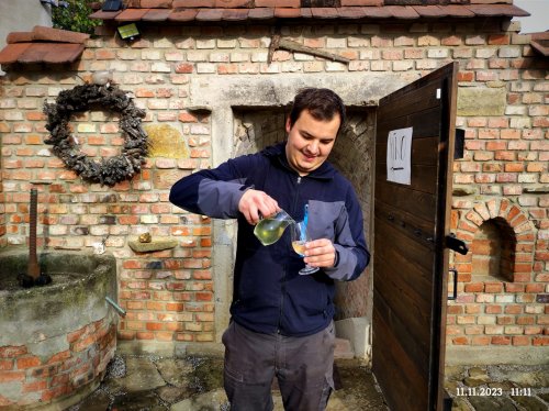 Dominik Labuda nalévá bílé víno ze džbánku.