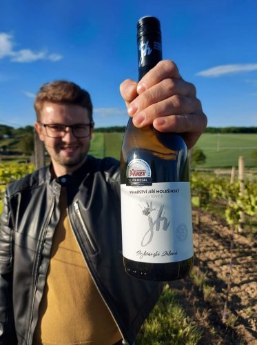 Vinařství Jiří Holešínský - vinař drží v ruce lahev, kde je odrůda Sylvánské zelené.