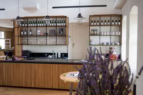 Interiér degustačních prostor Vinařství Zilvar - pult, v řadě vystavené lahve, industriální světla, kytice levandule